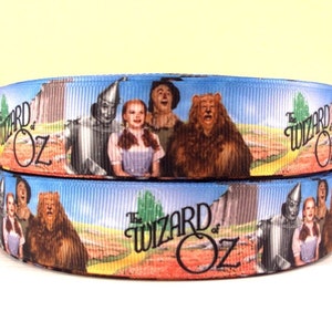 May include: Two rolls of blue and white ribbon with a printed image of the characters from the Wizard of Oz. The ribbon features the text "The Wizard of Oz" and images of Dorothy, the Scarecrow, the Tin Man, and the Cowardly Lion.