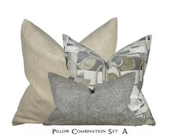 May include: A set of three decorative throw pillows. The pillows are in a neutral color scheme of beige, gray, and white. The patterned pillow features a geometric design with abstract shapes. The text "Pillow Combination Set A" is printed below the pillows.