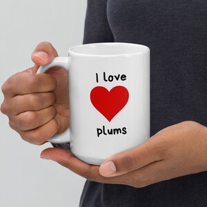 May include: White ceramic mug with a red heart and the text "I love plums".