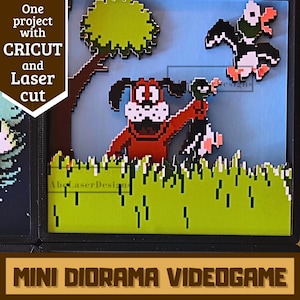 Puede incluir: Un mini diorama con arte pixelado de un perro y patos en un campo de hierba, que recuerda a un videojuego clásico. El diorama está cortado con láser e incluye el texto "One project with CRICUT and Laser cut" y "MINI DIORAMA VIDEOGAME".