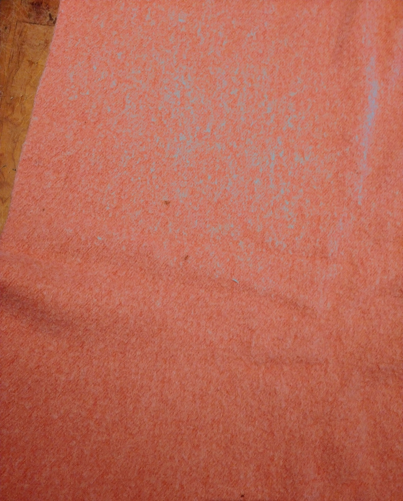 Op de afbeelding: Een close-up van een textuur, perzikkleurig stofoppervlak.