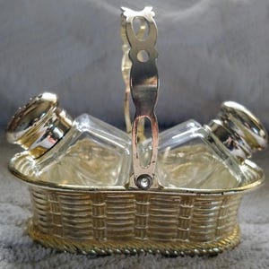 May include: A gold-tone salt and pepper shaker set in a basket-shaped holder with a handle. The shakers are clear glass with silver tops.