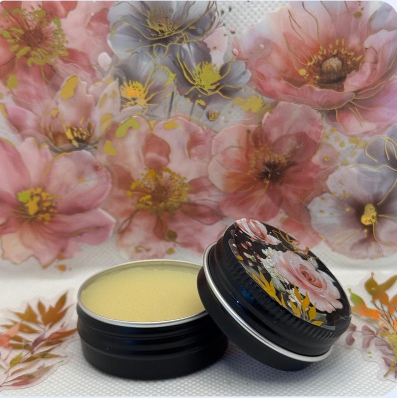 May include: A small black tin with a floral design lid containing a yellow lip balm.