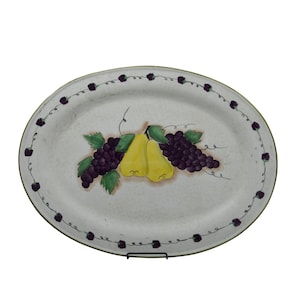 Puede incluir: Fuente ovalada para servir con un diseño pintado a mano que presenta peras amarillas, uvas moradas y hojas verdes. El borde está decorado con un patrón repetido de bayas moradas. La fuente tiene un fondo moteado blanquecino y un borde verde oscuro.