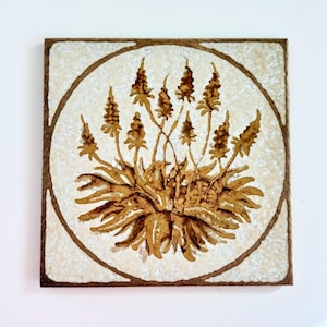 May include: A square ceramic tile featuring a brown botanical illustration of a plant with multiple spiky flower stalks centred within a circular frame. The background has a textured, off-white, and cream-coloured mottled finish.