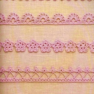 May include: Five different pink crochet lace trims, each with a unique pattern. The trims are arranged in rows on a light beige fabric background.