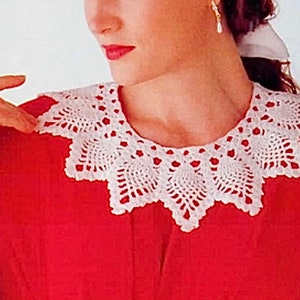 May include: A white crocheted collar with a scalloped edge. The collar is made of delicate, lacy stitches and has a vintage look.