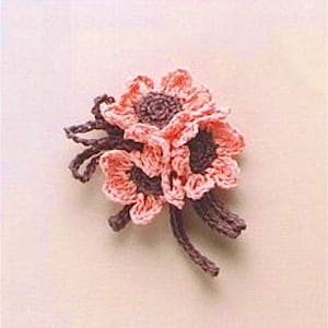 May include: A crocheted flower brooch featuring three pink flowers with brown centres and stems.