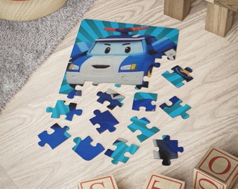 Op de afbeelding: Een puzzel voor kinderen met een blauwe en witte cartoon politieauto. Sommige stukjes zijn in elkaar gezet, andere liggen verspreid op een licht houten oppervlak. Houten blokken en een speelgoedringtoren zijn zichtbaar.
