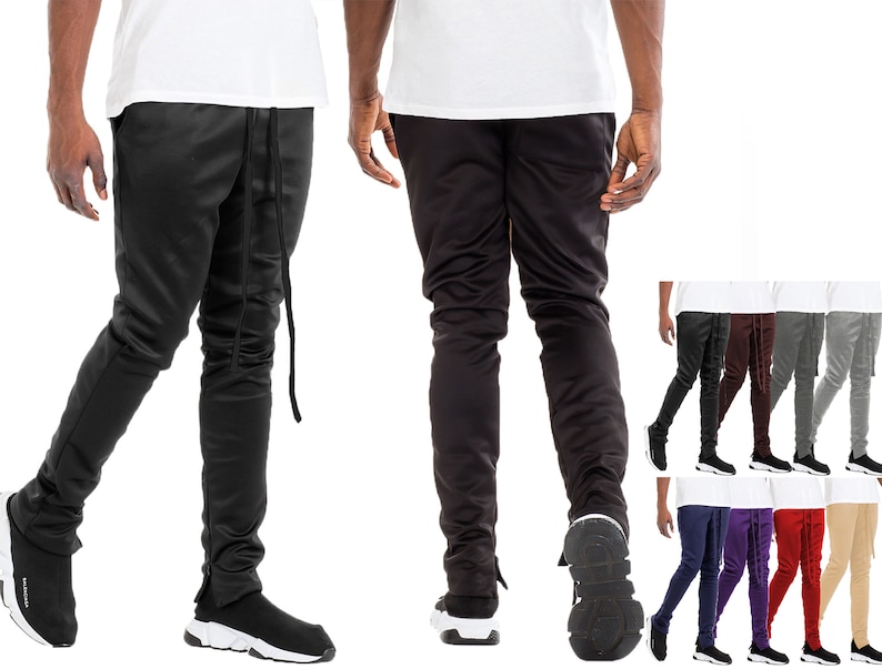 May include: Black track pants with a drawstring waist and ankle zippers. The pants are shown in multiple colors, including black, brown, gray, and beige. The pants have a slim fit and are made of a smooth material.
