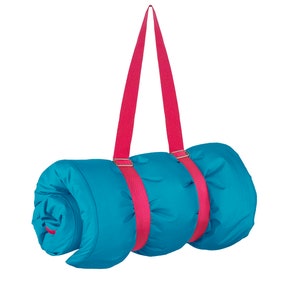 May include: A rolled-up blue sleeping bag with pink straps. The straps have metal buckles and are designed to be carried over the shoulder.