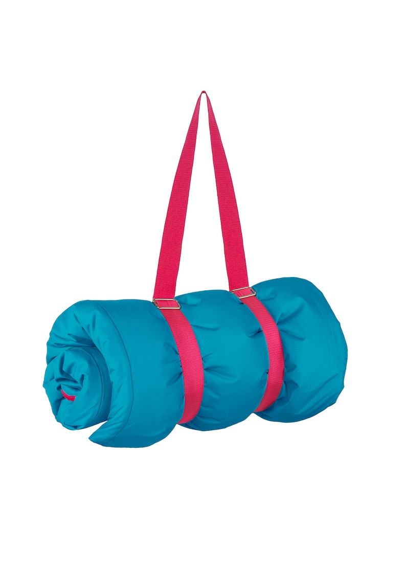 May include: A rolled-up blue sleeping bag with pink straps. The straps have metal buckles and are designed to be carried over the shoulder.