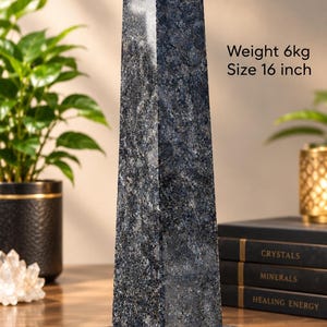 Pode incluir: Um obelisco de pedra salpicada em azul escuro e cinza sobre uma base circular de mármore preto. O obelisco apresenta um topo piramidal pontiagudo e contém o texto Weight 6kg e Size 16 inch, indicando as suas especificações físicas.