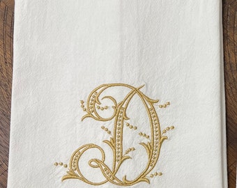 May include: White kitchen towel with a gold embroidered letter D.
