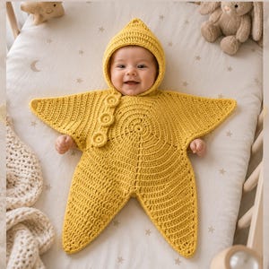 Pode incluir: Um saco de dormir de crochê em forma de estrela amarelo-brilhante para bebé, com capuz pontiagudo e três botões circulares na lateral. A peça é feita com um padrão de pontos texturizado que irradia do centro, formando cinco pontas distintas.