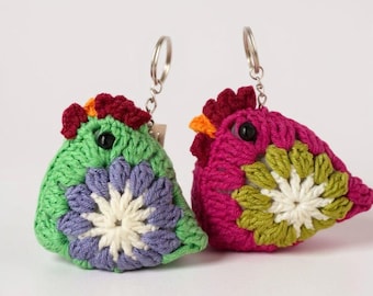 May include: Two handmade crochet bird keychains. One is green with purple and white accents, the other is pink with green and white accents. Both have black eyes, red crests, and silver key rings. These charming keychains are perfect for bird lovers.