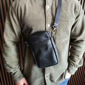 Genuine leather messenger bag in black color. Messenger shoulder bag with regulated strap length and metal furtinure