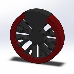 May include: A 3D-rendered wheel design featuring a black center with curved cutouts and a dark red outer rim. The wheel has a circular shape and is set against a white background.