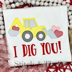May include: A yellow toy excavator with a gray bucket is digging up pink and red hearts. The text "I DIG YOU!" is written in red below the excavator.