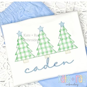 May include: A white onesie with a green and white plaid Christmas tree design and the name "caden" embroidered in blue. The onesie is paired with a light blue pair of shorts.