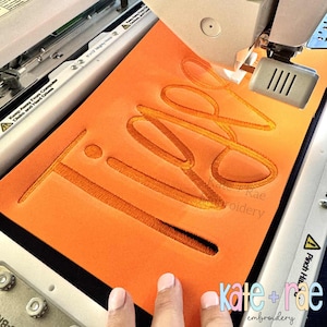 Puede incluir: Una tela naranja con la palabra "TIPS" bordada con hilo dorado por una m&aacute;quina. El texto "kate + rae embroidery" es visible en la esquina inferior derecha.