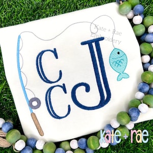 May include: White t-shirt with a blue fishing rod and a fish attached to a line. The shirt features the embroidered letters "CCJ" in navy blue. The text "Kate + Rae Embroidery" is also visible.
