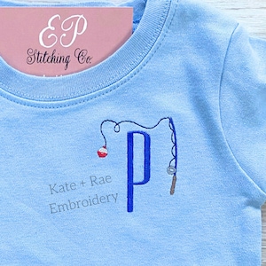 May include: Light blue t-shirt with a blue embroidered letter "P" with a fishing rod and bobber. The text "Kate + Rae Embroidery" is also embroidered on the shirt.