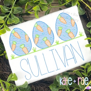 May include: Embroidered design featuring three blue eggs with orange carrots inside, a green grass border, and the name "SULLIVAN" in blue thread.
