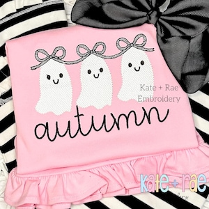 May include: Pink shirt with a ruffle hem featuring three embroidered ghosts with bows and the word "autumn". The shirt is from Kate + Rae Embroidery.