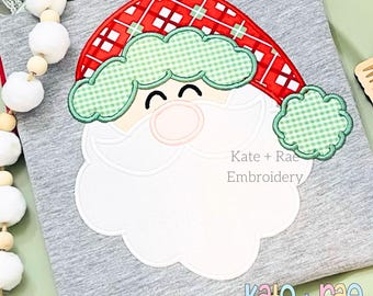 May include: White applique of a smiling Santa Claus with a red and green plaid hat and a white beard. The applique is on a gray background with the text "Kate + Rae Embroidery" below it.
