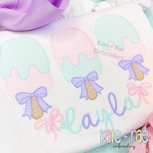 May include: A white t-shirt with three embroidered ice cream cones with bows and the text "Playful" and "Kate + Rae Embroidery" in pastel colors.