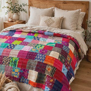 Könnte beinhalten: Eine rechteckige Patchwork-Decke mit einer lebendigen Anordnung aus bunten Stoffquadraten. Die Decke zeigt verschiedene Muster, darunter florale, geometrische und gepunktete Drucke in den Farben Pink, Blau, Orange, Grün und Violett.
