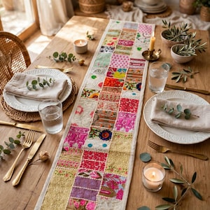 Puede incluir: Un camino de mesa rectangular largo que presenta un diseño de patchwork de varios cuadrados de tela bordados y coloridos. El camino muestra una mezcla vibrante de patrones en rosa, rojo, amarillo, verde y dorado con costuras intrincadas.