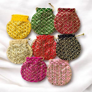 Puede incluir: Una colección de ocho pequeñas bolsas de cordón coloridas. Cada bolsa es de un color diferente, incluyendo amarillo, verde, rojo, negro, dorado, rosa y magenta. Las bolsas están decoradas con un patrón repetido de adornos dorados.