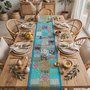 Peut inclure: Un long chemin de table rectangulaire doté d'une base turquoise vive avec un motif patchwork composé de broderies florales et géométriques complexes et multicolores. Le chemin est centré sur une table à manger en bois avec des assiettes.