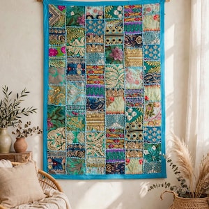 May include: A rectangular wall hanging featuring a patchwork of various fabric squares in shades of teal, gold, pink, and green. The textile is embellished with intricate embroidery, sequins, and metallic threads, framed by a solid teal border.