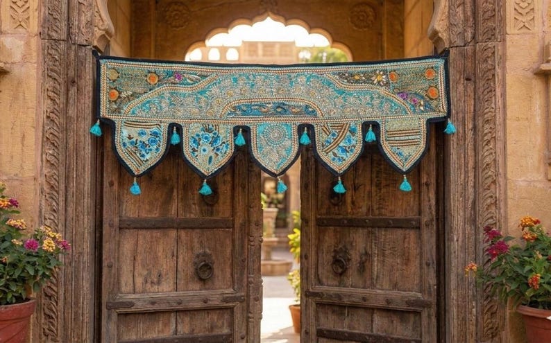May include: A decorative textile door hanging with a turquoise and black design. The hanging features floral patterns, tassels, and intricate embroidery. It is displayed over a set of wooden doors, adding a touch of bohemian style.