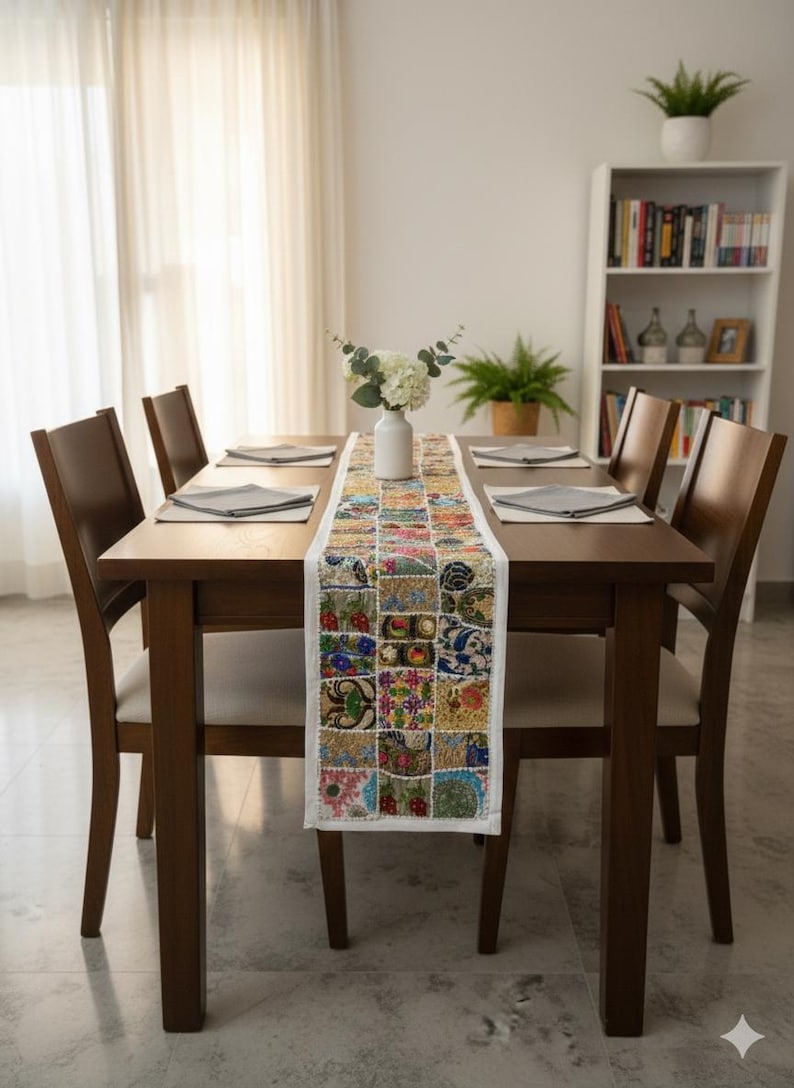 May include: A dining table set for six with a colourful patchwork table runner. The table is made of dark wood, and the chairs have light-coloured seats. A white vase with flowers sits on the runner.