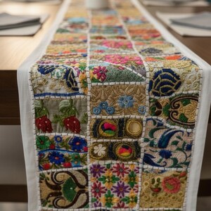 May include: A vibrant patchwork table runner with embroidered squares. The runner showcases floral and geometric patterns in blue, green, red, and gold. The edges are trimmed with white fabric.