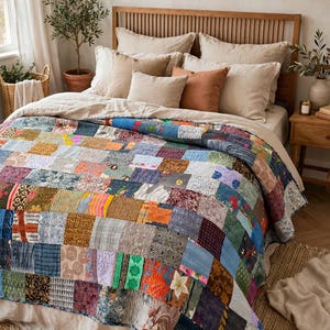 Puede incluir: Una colcha de patchwork que presenta una cuadrícula de varios cuadrados de tela en diversos colores, patrones y texturas. La colcha está construida con numerosas piezas pequeñas y rectangulares de tela cosidas juntas, mostrando una amplia gama de estampados.