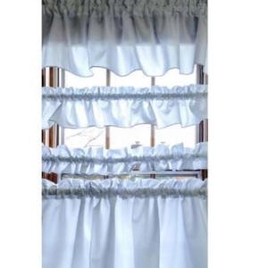 May include: White ruffled window curtains. The curtains are made of a soft, flowing fabric and are designed to add a touch of elegance to any room. The curtains are layered, with multiple tiers of ruffles.