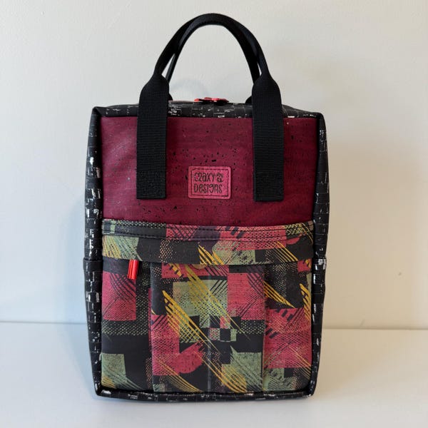 The finished Mini Cork Backpack by Craxy Designs, showing the natural cork body, printed contrast pocket, rivetted hardware and stitched maker's tag