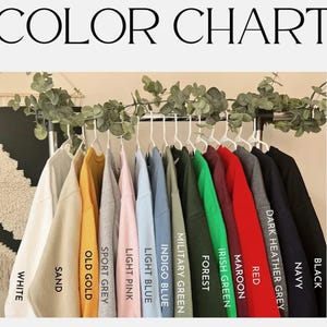 May include: A color chart displays a variety of clothing items in different colors. The colors include white, sand, old gold, sport grey, light pink, light blue, indigo blue, military green, forest, irish green, maroon, red, dark heather grey, navy, and black.