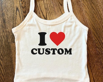 May include: White tank top with black text that reads "I ♥ CUSTOM" with a red heart symbol. The top has thin straps and a scoop neckline.