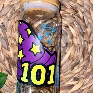 May include: A clear glass jar with a bamboo lid. The jar features a purple wizard hat design with yellow stars and the number "101" in yellow. A blue design is also visible on the jar.