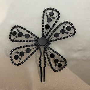 May include: Black flower-shaped hair comb with rhinestones and a black metal stem.
