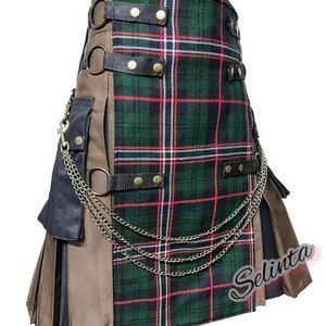 Puede incluir: Un kilt a cuadros verdes, rojos y blancos, con detalles marrones y negros. Cuenta con anillos metálicos, correas y una cadena decorativa. El kilt tiene un diseño plisado y un bolsillo lateral.