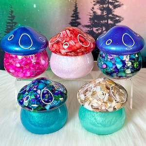 以下が含まれることがあります： 貝殻のデザインが施された、カラフルなキノコ型の樹脂製の小箱が5つ。各箱は光沢のある虹色の仕上げになっています。