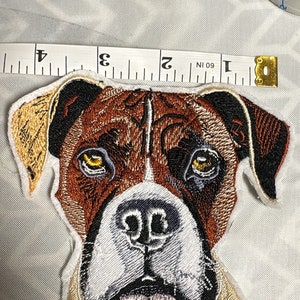 May include: Embroidered patch of a boxer dog's face. The dog has brown and white fur, with a black nose and brown eyes. The patch is approximately 2 inches wide.