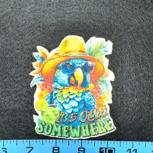 May include: A colorful sticker featuring a blue parrot wearing sunglasses and a yellow hat. The parrot is holding a cocktail and the text "It's 5 O'Clock Somewhere" is displayed below. The sticker is approximately 3 inches wide.